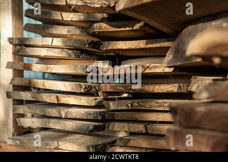 Aria-asciugando segato palo di lastra di legno di tavola sotto baldacchino a casa cortile preparato per carpenteria fai da te hobby. Negozio di legno nel cortile della casa. Materiale in legno Foto Stock