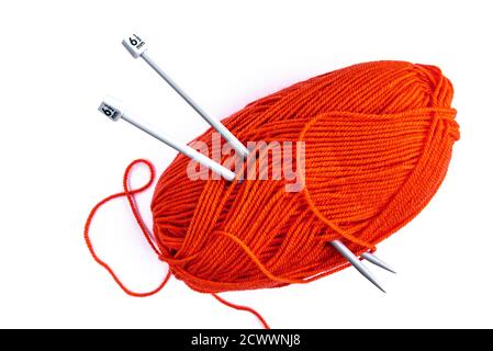 Palla di lana d'arancia con aghi in maglia su bianco. Foto Stock