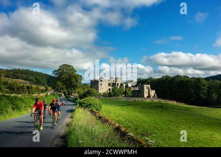 Gli uomini socializzano in bici da strada mentre si passa davanti alla Torre di Barden nello Yorkshire Dales National Park in una bella giornata estiva, nel Nord Yorkshire, Regno Unito Foto Stock