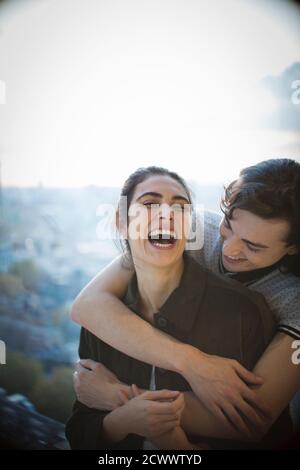 Felice giovane coppia ridendo e abbracciando sul balcone Foto Stock
