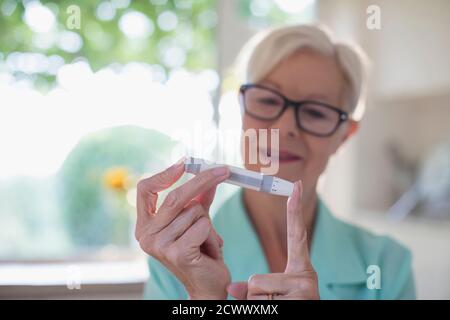 Donna anziana con diabete usando il glucometro del sangue sul dito Foto Stock