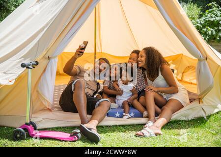 Felice famiglia che prende selfie con la fotocamera del telefono all'interno della tenda estiva Foto Stock