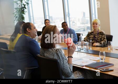 Donna d'affari sorridente che beve caffè nella sala conferenze Foto Stock