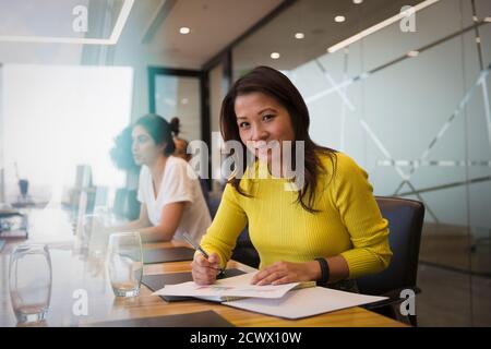 Ritratto sorridente imprenditrice con la documentazione in sala conferenza incontro