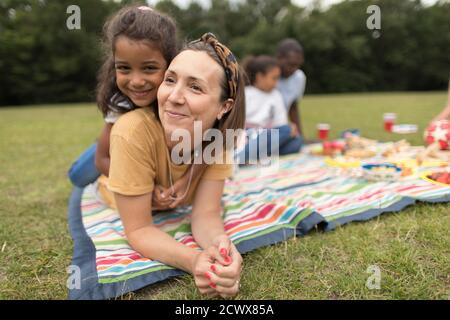 Ritratto felice madre e figlia rilassarsi su coperta da picnic in parcheggio Foto Stock