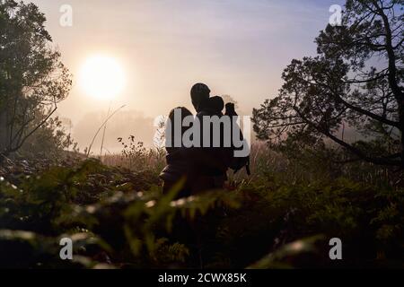 Silhouette giovane coppia serena godendo il tramonto nella natura Foto Stock