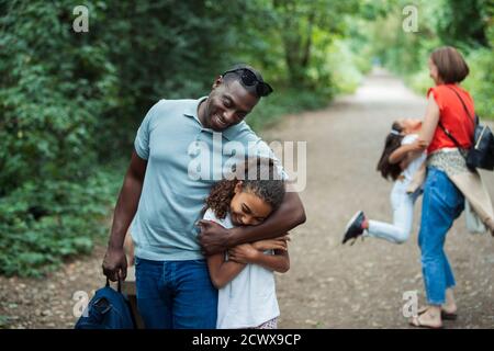 Felice padre e figlia abbracciano sul sentiero del parco Foto Stock