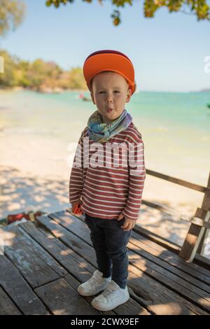 Moda bambino. Modello di ragazzo felice. Piccolo ragazzo di stile nel baseball. Bel ragazzo. Sneaker bianchi, tappo rosso. Foto Stock