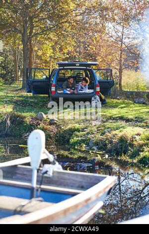 Giovane coppia che si distende in macchina al sole lago d'autunno Foto Stock