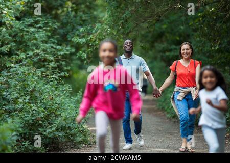 Felice famiglia a piedi e correre su sentiero in boschi Foto Stock