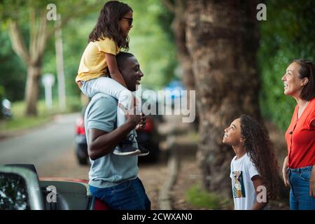 Famiglia felice che parla fuori convertibile in strada Foto Stock