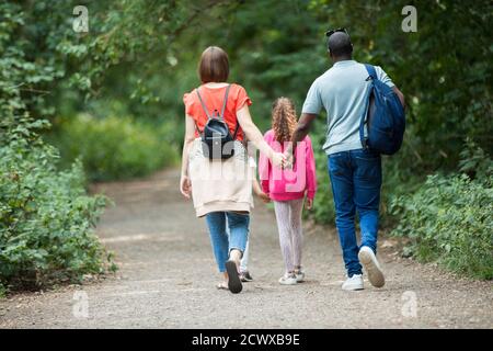 Famiglia che tiene le mani che camminano sul sentiero nei boschi Foto Stock