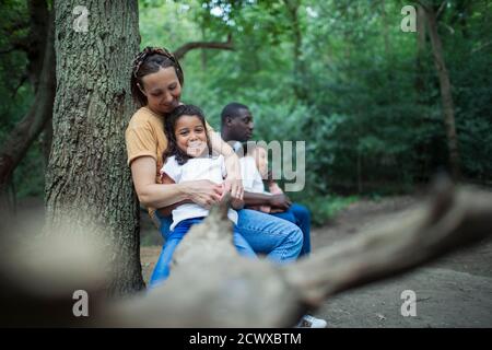Famiglia felice rilassarsi su log caduto su escursione in boschi Foto Stock