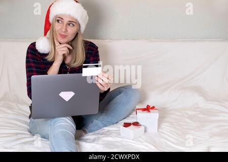 Natale, concetto di shopping online a x-mas. Donna in cappello santa con scatola regalo, computer portatile e carta di credito. Vendite di vacanze invernali. Foto Stock
