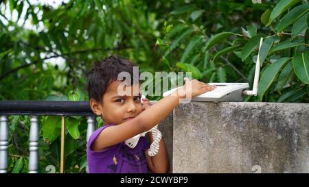 Una piccola ragazza indiana che usa il telefono. Bambino che gioca il telefono all'aperto Foto Stock