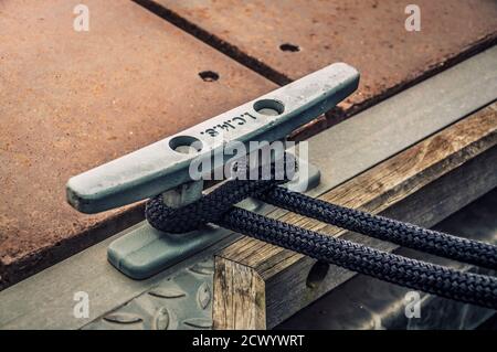 Primo piano della cleat del dock con una fune legata intorno ad essa. Concetto visivo di connessione come barca legata e collegata al pontile. Foto Stock