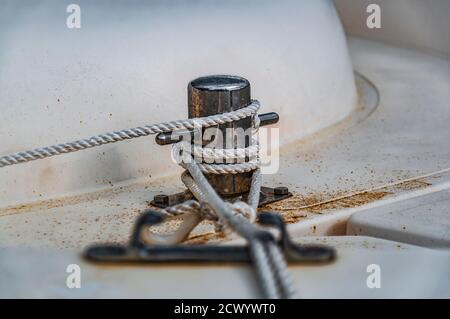 Primo piano del paletto della barca con una corda legata intorno ad esso. Concetto visivo di connessione come barca legata e collegata al pontile. Foto Stock