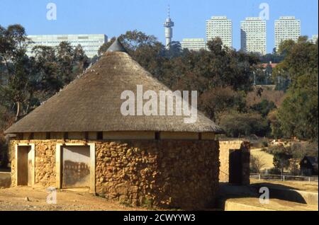 Skyline di Johannesburg di edifici moderni, tra cui la Torre della TV di Hillbrow, con un tradizionale rondavel in primo piano, Sud Africa 1981 Foto Stock