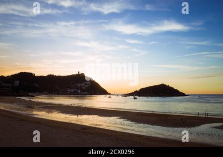 Donostia, Gipuzkoa, Paesi Baschi, Spagna - 12 Luglio 2019 : il tramonto cade sulla spiaggia di la Concha. Montagna Igeldo sullo sfondo. Foto Stock