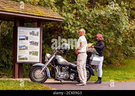 Shenandoah Valley, VA, USA 09/27/2020: Una coppia interracial (uomo caucasico anziano e donna afroamericana) sta in piedi dalla loro moto cercando Foto Stock