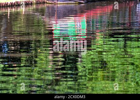 Forme astratte create dai riflessi di strette dipinte di luce barca in acqua Foto Stock