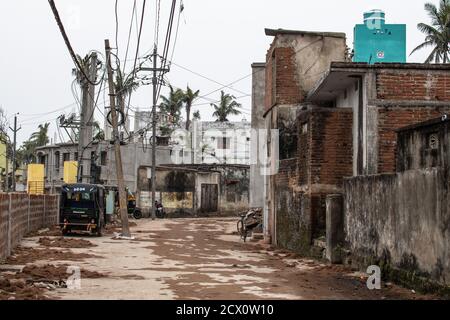 Puri, India - 3 febbraio 2020: Una strada rurale e vuota con rickshaws cng parcheggiato vicino a diversi edifici il 3 febbraio 2020 a Puri, India Foto Stock