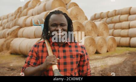 Ritratto di giovane agricoltore africano con forchetta a caraffa sulle spalle. Foto di alta qualità Foto Stock