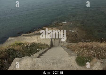 Scale giù verso le rovine di una piattaforma militare tedesca da Seconda guerra mondiale sulla costa del mare del nord vicino a Boulogne sur mer Foto Stock