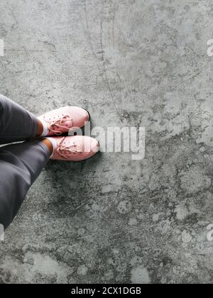 Vista dall'alto, dettagli della vecchia scarpa in pelle tonalità marrone sul pavimento in cemento grunge, piedini Selfie che indossano scarpe da ginnastica sul pavimento. Foto Stock