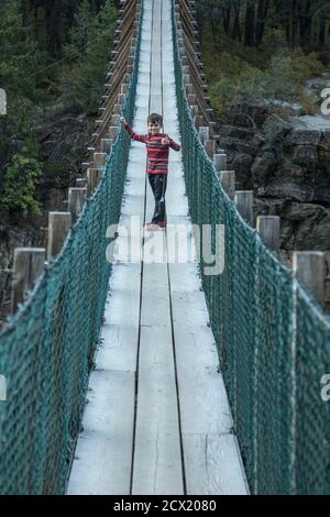 Young Boy attraversa il ponte sospeso Foto Stock