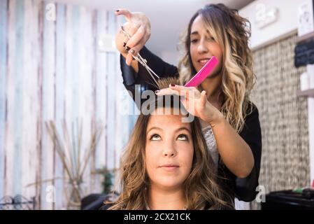 Donna dai capelli lunghi che ottiene il taglio dei capelli ad un salone di bellezza del parrucchiere Foto Stock
