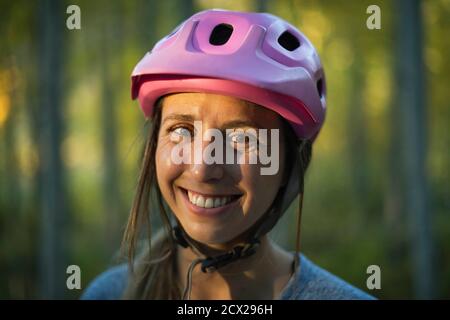 Primo piano ritratto di una giovane donna sorridente che indossa un casco da ciclismo Foto Stock