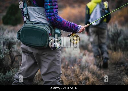 Sezione centrale della donna che tiene la canna da pesca del mosca Foto Stock