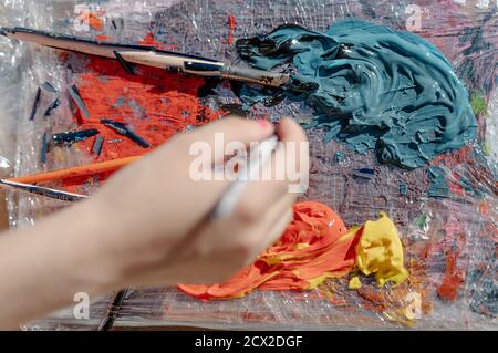 mano con un pennello che prende un colore da una tavolozza di pittura. Foto orizzontale superiore Foto Stock