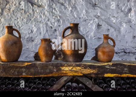 Varie vecchie caraffe, piatti di enologo su una mensola in legno nella cantina Foto Stock