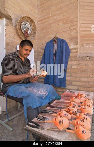 Puppet maker pittura le teste dei burattini, Khiva, Uzbekistan Foto Stock