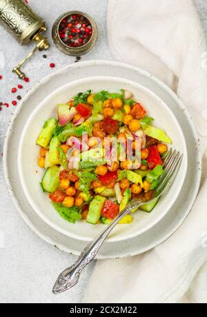 Salutare e deliziosa insalata vegetariana o vegana con ceci, lattuga, avocado, cetriolo, pomodori, cipolla rossa, olio d'oliva e spezie da vicino. Selettivo Foto Stock