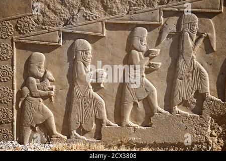 Intricate sculture lungo il Palazzo di Dario il Grande, conosciuto anche come la Tachara, Persepoli, Shiraz, Iran. Vari delegati di diverse tribù che portano tributi. Foto Stock