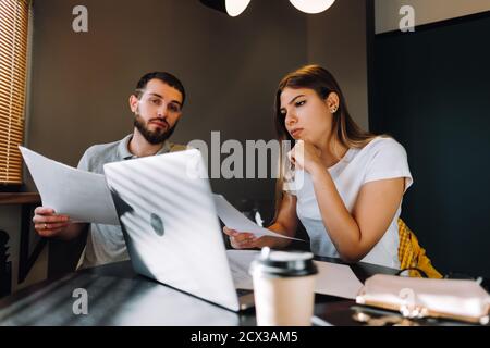 Couple gestisce le finanze guardando attraverso i loro conti bancari utilizzando un computer portatile. Foto Stock