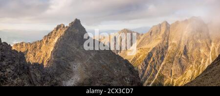 Particolare di Foggy montagna cime all'alba con luce dorata in alta Tatra, Slovacchia Foto Stock