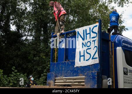 Denham, Regno Unito. 28 Settembre 2020. Un ufficiale della polizia della Thames Valley parla ad un attivista anti-HS2 fissato con una grande corda intorno al collo che sta bloccando un HGV utilizzato per lavori connessi al collegamento ferroviario ad alta velocità HS2. Gli attivisti ambientali continuano a cercare di prevenire o ritardare i lavori sul controverso progetto £106 miliardi per il quale la fase di costruzione è stata annunciata il 4 settembre da una serie di campi di protezione basati lungo il percorso della linea tra Londra e Birmingham. Credit: Mark Kerrison/Alamy Live News Foto Stock