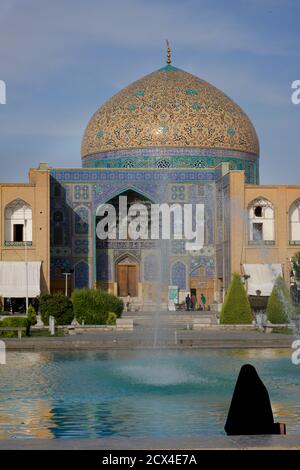 Donna iraniana vestita di nero di fronte alla moschea di Lotfollah, e fontana in Piazza Imam. Isfahan, Iran Foto Stock