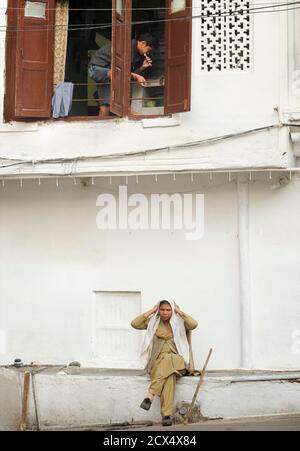 Scena candida. Donna indiana che asciuga i capelli e l'uomo che spazzolava i denti sopra. Udaipur, Rajasthan, India Foto Stock