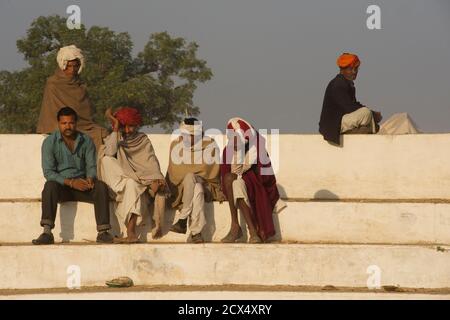 Uomini Rajasthani seduti a parlare sui gradini dello stadio. Pushkar, Rajasthan, India Foto Stock