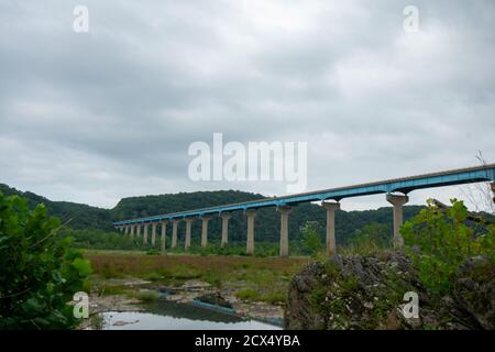 Guardando tra piante e rocce al Ponte del Bosco Norman Sopra il fiume Susquehanna su un cielo nuvoloso Foto Stock