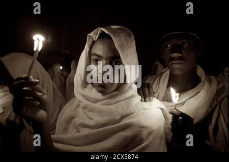 Pellegrini etiopi e adoratori che celebrano Fasika nella chiesa di Bet Medhame Alem. Pasqua, Lalibela, Etiopia UN Kuta è un tessuto fatto a mano molti uomini etiopi usano per coprire la testa e le spalle quando indossano abiti fatti di chiffon, specialmente quando frequentano la chiesa. È costituito da due strati di tessuto Foto Stock