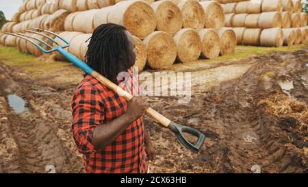 Ritratto di giovane agricoltore africano con forchetta a caraffa sulle spalle. Foto di alta qualità Foto Stock