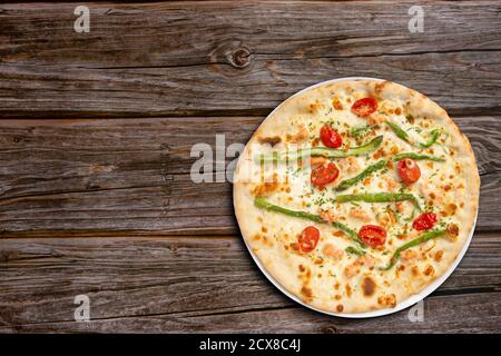 Pizza vegetariana con asparagi e pomodori ciliegini vista dall'alto su sfondo di legno. Foto Stock