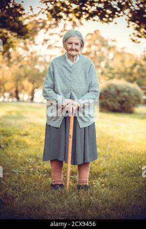 Ritratto di donna anziana con bastone nel parco autunnale Foto Stock