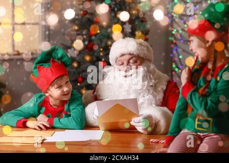 Elf bambini con Babbo Natale lettera di lettura a casa Foto Stock